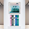 Framed Palms print by Nick Purser displayed on a gallery wall above five decorated postal tubes.